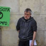 En la fotografía aparece Jorge Riechmann al lado de un cartel de fondo verde y letras negras donde aparece escrito "Se agota el tiempo"