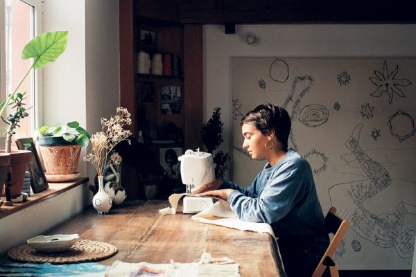 Fotografía analógica en la que se retrata a una mujer sentada en un escritorio de madera